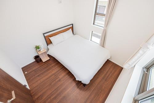 a bedroom with a white bed and a wooden floor at 春明House in Tokyo