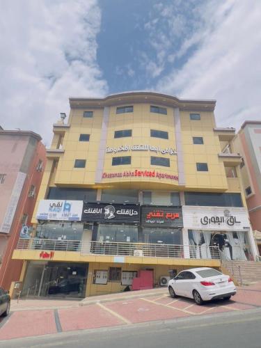 a yellow building with a car parked in front of it at خزامى ابها للشقق المخدومة in Abha
