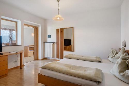 a white bedroom with two beds and a television at Seaberhof Kaltern in Caldaro