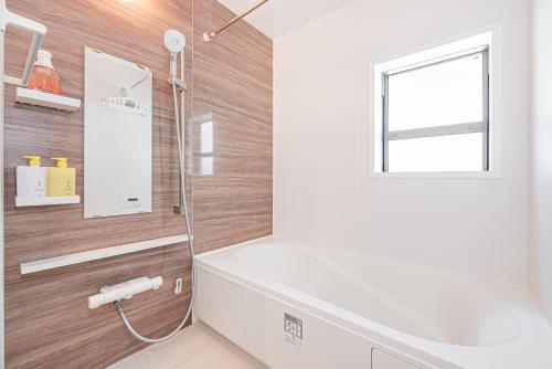 a bathroom with a white tub and a window at 春明House in Tokyo
