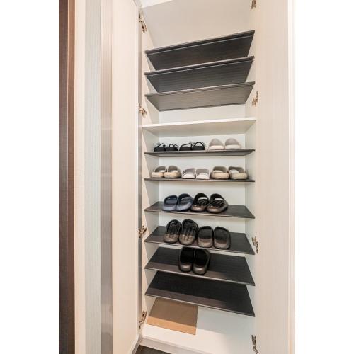a walk in closet with black shelves and shoes at 春明House in Tokyo