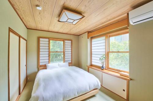 a bedroom with a large white bed and windows at プライベートリゾート飛鳥 in Atami