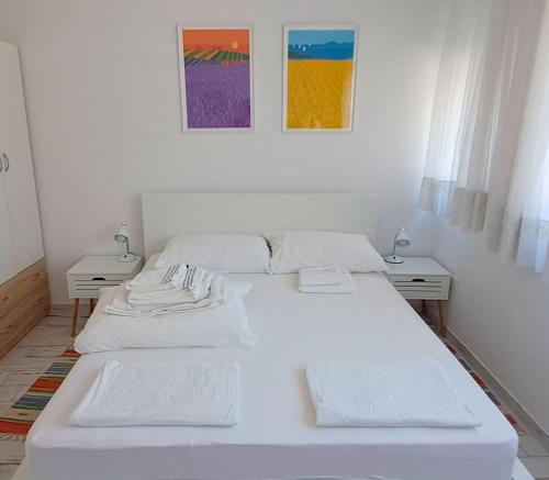 a white bedroom with two beds and two tables at Apartmani Mentha & Lipa in Novi Vinodolski