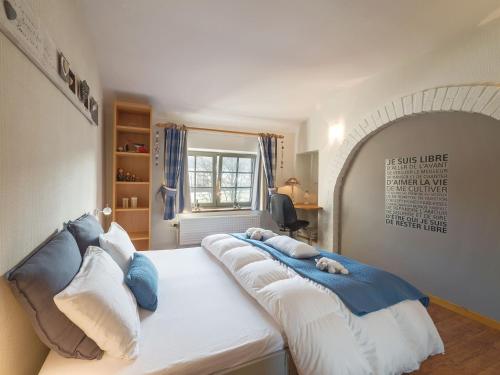 a bedroom with a large bed with blue and white pillows at Clos Du Ry De Snaye in Beauraing