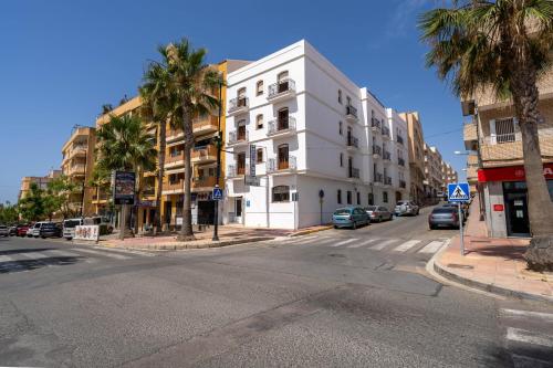 a white building on a city street with palm trees at BF Rooms Garrucha in Garrucha