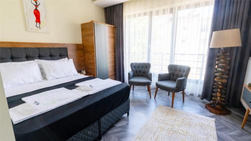 a bedroom with a bed and two chairs and a window at Elegance Sirius in Kayseri