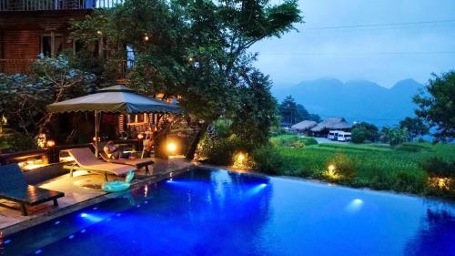 a swimming pool with lights in a backyard at night at Pu Luong Jungle Lodge in Pu Luong