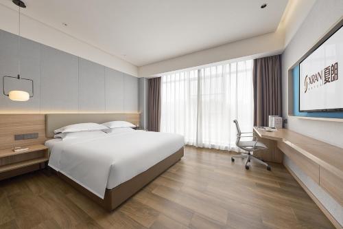 a bedroom with a bed and a desk and a television at 夏朗酒店 Xialang Hotel in Guangzhou
