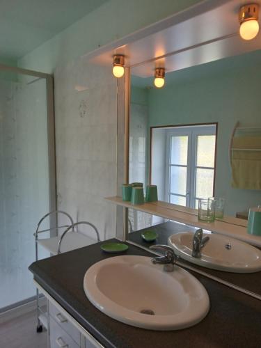une salle de bain avec deux lavabos et un grand miroir dans l'établissement Gîte le Lasnier, à Crasville