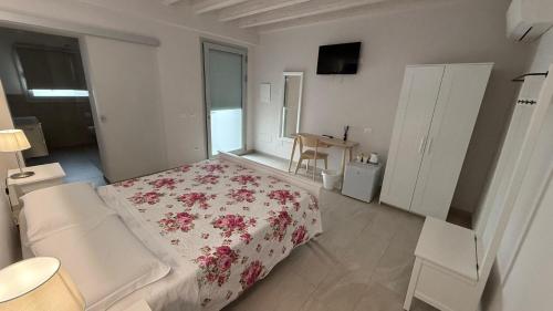 a white bedroom with a bed with a floral blanket at La corte di Emma e Ale in Volta Mantovana