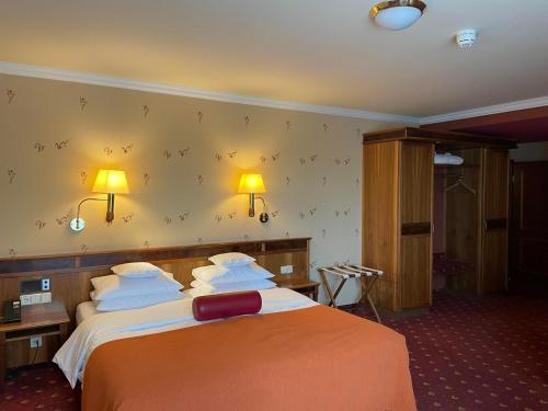 a hotel room with a bed and two lamps on the wall at Hotel Zum Stein Wellness & Genuss Resort in Oranienbaum-Wörlitz