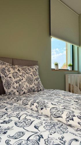 a bed with a blue and white comforter and a window at Liwia Park Green House in Niechorze