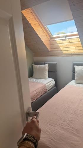 a person opening a door to a room with two beds at Liwia Park Green House in Niechorze