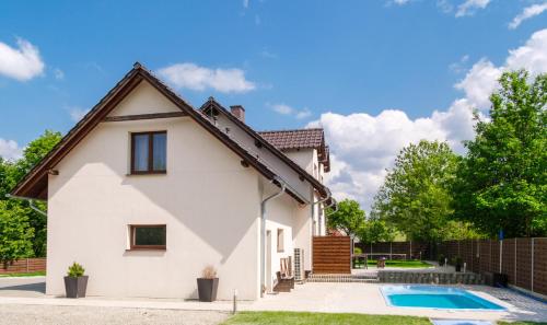 a white house with a swimming pool at Apartament Sosnówka B2 z basenem i strefą SPA in Sosnówka