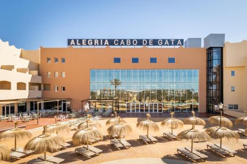 a resort with chairs and umbrellas in front of a building at ALEGRIA Cabo De Gata in Retamar