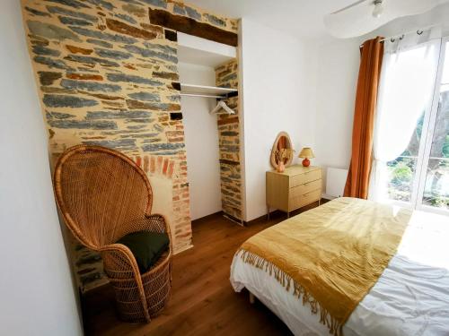 une chambre avec un lit et un mur en pierre dans l'établissement La Basque - un balcon au coeur de La Gacilly, à La Gacilly