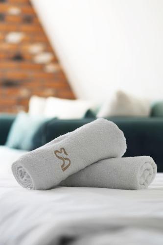 a pile of towels sitting on top of a bed at Elite Apartments Piwna Prestige in Gdańsk