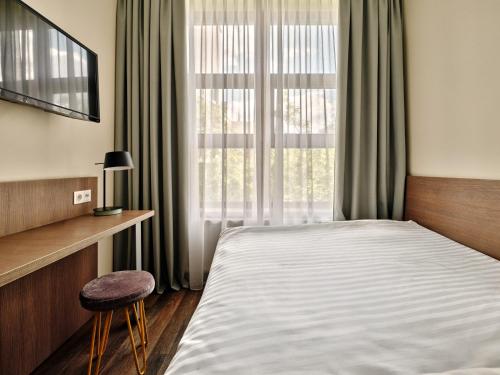 a bedroom with a bed and a chair and a window at Garner Hotel Berlin - Schöneberg by IHG in Berlin