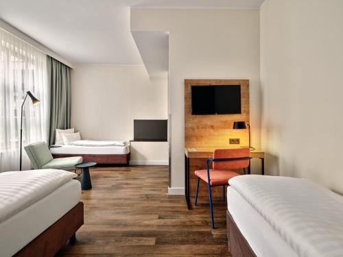 a hotel room with two beds and a desk at Garner Hotel Berlin - Schöneberg by IHG in Berlin