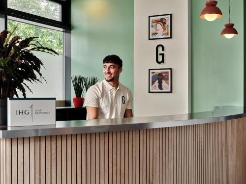 a man is standing behind a counter in an office at Garner Hotel Berlin - Schöneberg by IHG in Berlin
