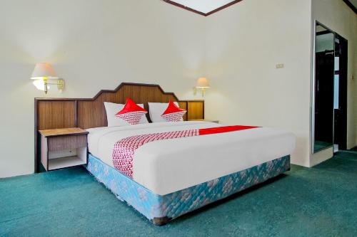 ein Schlafzimmer mit einem großen weißen Bett mit roten Kissen in der Unterkunft OYO 2360 Hotel Rio in Bengkulu