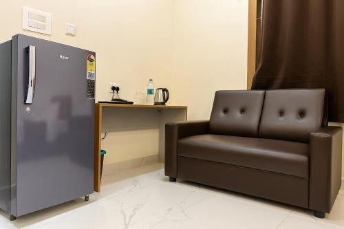 a living room with a chair and a refrigerator at Jay & Jas Hotel in Tirupati