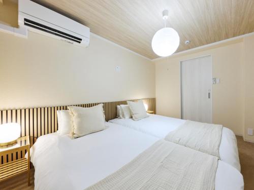 two white beds in a bedroom with a ceiling at tokyo Japandi apartment ikebukuro in Tokyo