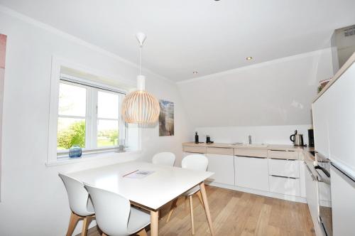 a white kitchen with a white table and chairs at Altes Pastorat Appartement Altes Pastorat 6 in St. Peter-Ording