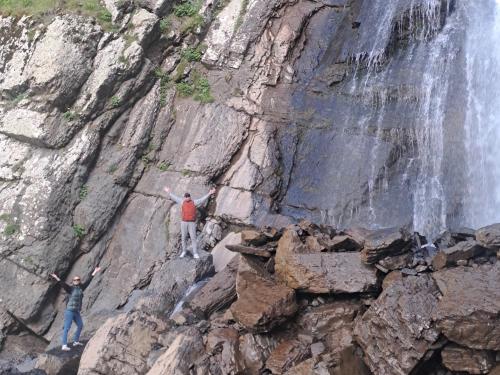 two men standing on a cliff next to a waterfall at Xinaliq Khinalig İzzet's Riverside Home Stay in Xınalıq