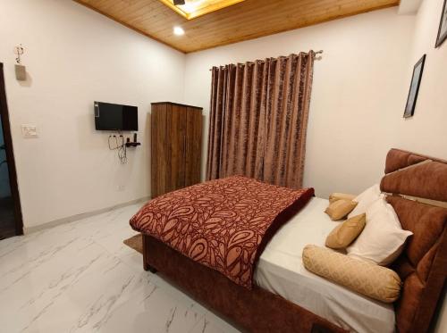 a bedroom with a bed and a television in it at Claremont Homestay By StayApart in Kasauli