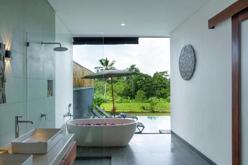 a bathroom with a tub and a sink and an umbrella at Alam Dana Ubud in Ubud