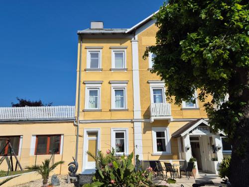 a yellow building with white windows and a tree at Hotel Hotwagner in Maria Enzersdorf