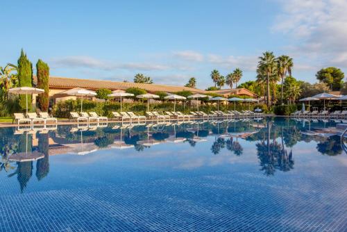 a large swimming pool with chairs and umbrellas at Valentin Playa de Muro in Playa de Muro