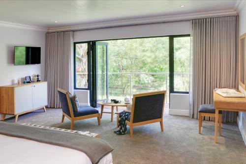 a hotel room with a bed and a large window at Knysna Hollow Country Estate in Knysna
