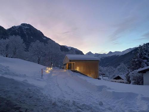 a building in the snow with mountains in the background at Haus Albuin in Sankt Gallenkirch