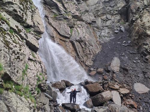 a man standing in front of a waterfall at Xinaliq Khinalig İzzet's Riverside Home Stay in Xınalıq