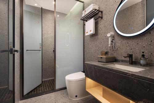 Un baño con lavabo, espejo e inodoro. en Wuxuan Hotel Zoo Branch, en Chongqing