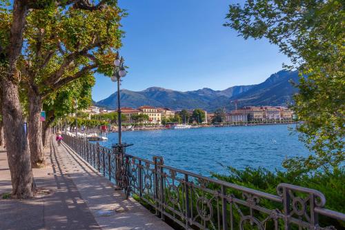 a fence next to a lake with mountains in the background at Viganello Modern Apartments in Lugano