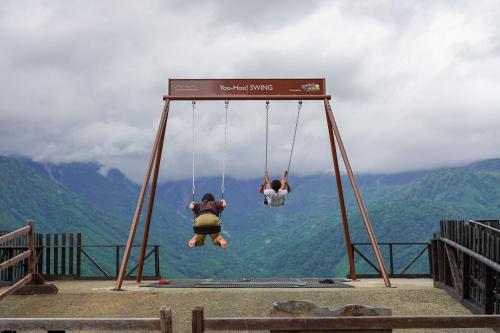 two people are swinging on a swing at Square 8 HAKUBA RETREAT by UNPLAN in Hakuba
