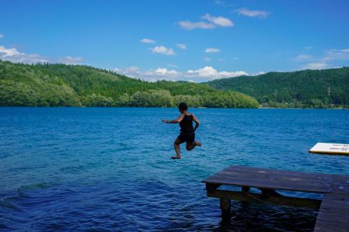 a person jumping off a dock into a lake at Square 8 HAKUBA RETREAT by UNPLAN in Hakuba