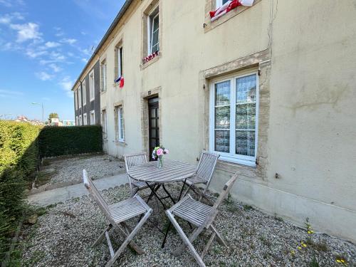 a table and chairs in front of a building at Les continents maison spacieuse 4 belles chambres parking privatif terrasse à 5 mn à pied tous commerces et 20 mn plage Omaha Beach et à 15 mn de Bayeux in Le Molay-Littry