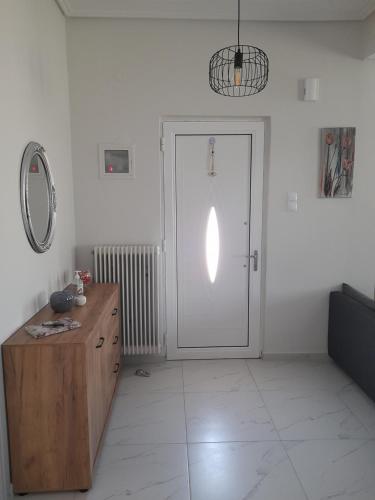a white room with a door and a wooden dresser at Meteora view Guesthouse in Kalabaka