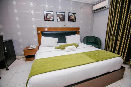a bedroom with a large bed with a green blanket at Elegance Suites Hotels in Lagos