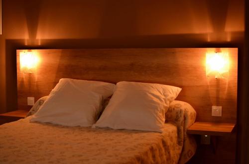 a bedroom with a bed with two pillows and two lights at Mistral Appartements in Saint-Louis-du-Rhône