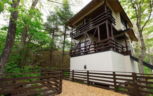 a building with a balcony in the middle of a forest at rinne 2nd living Kitakaruizawa Garden in Tsumagoi