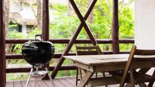 a table and chairs on a porch with a large window at rinne 2nd living Kitakaruizawa Garden in Tsumagoi