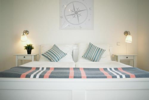 a white bed with striped pillows and a clock on the wall at Apartments Villa Ornamenta - 5min to beach - free parking in Kaštela