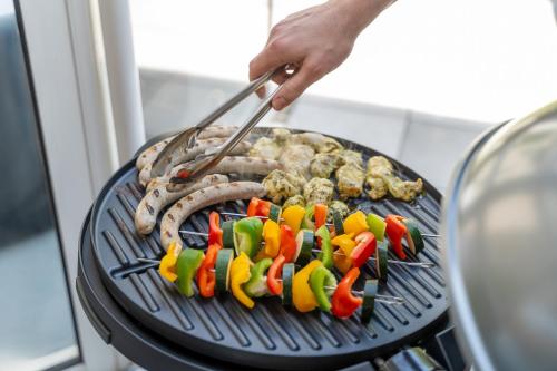 a person cooking meat and vegetables on a grill at flair Apartment Blossom I BBQ I 2xParken I Terrasse I Kaffee I Waschmaschine I Disney plus in Fulda