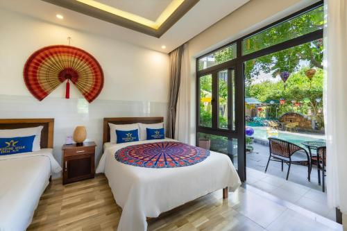 a bedroom with two beds and a view of a pool at Blessing Villa Hoi An in Hoi An