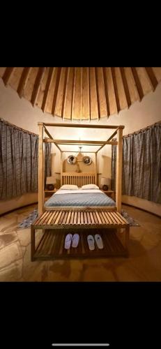 a bedroom with a canopy bed with a pair of slippers at The Fort Valley BnB , Karatu in Karatu